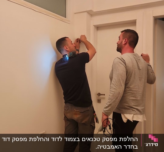 שני אנשים עובדים על התקנת חשמל בקיר